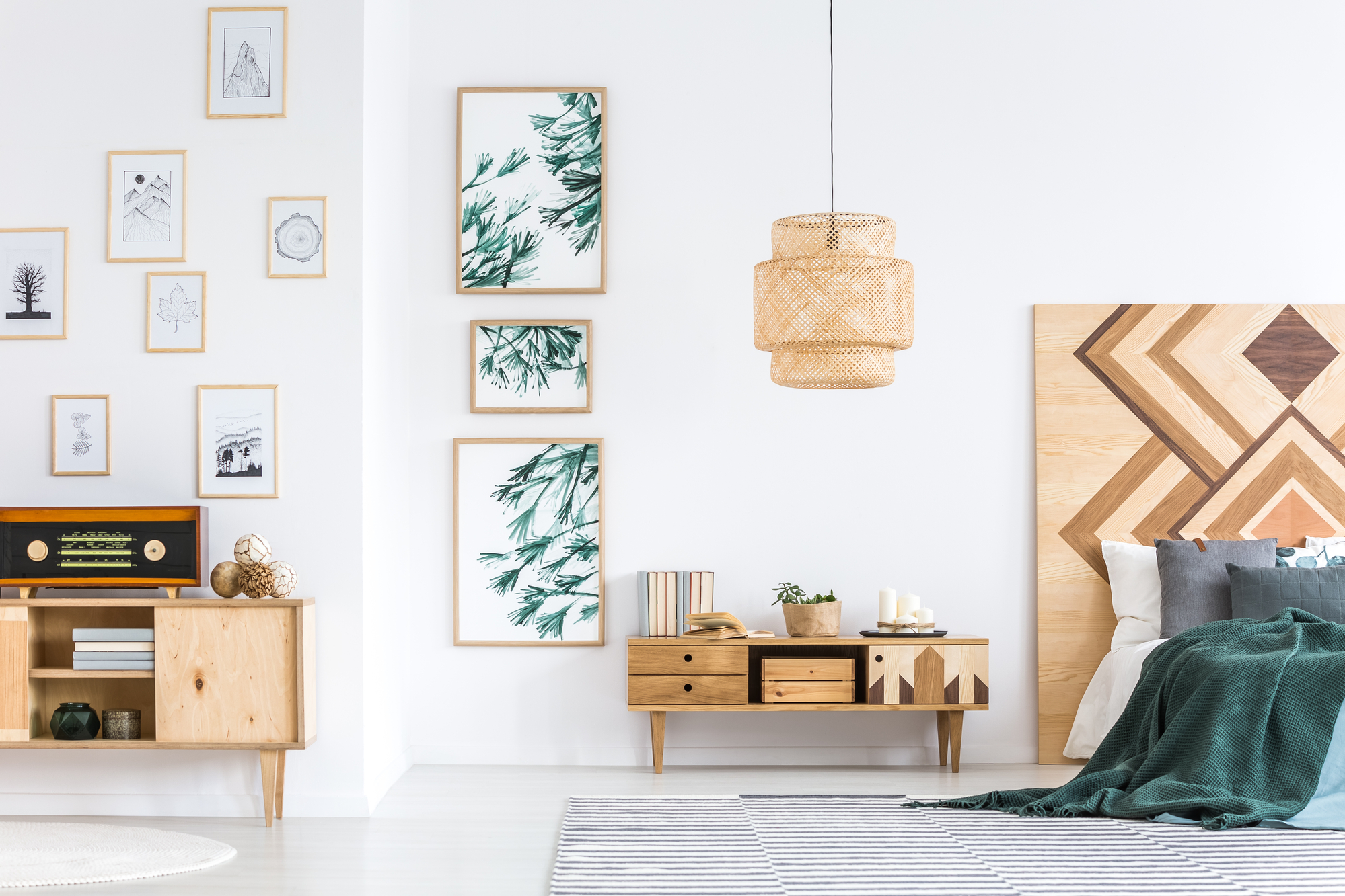 Retro radio on wooden rustic cupboard in bedroom interior with green posters on white wall